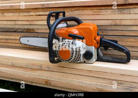 portable gasoline chain saw on a stack of wooden planks. Stock Photo