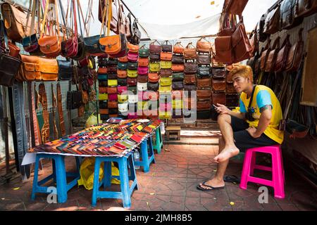 Street shops in Bangkok city. A shop selling colorful bags and a salesman male Stock Photo