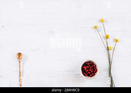 white floral background red dried berries spoon Stock Photo