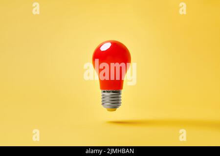 Red lightbulb levitate on yellow background. Idea, motivation concept Stock Photo