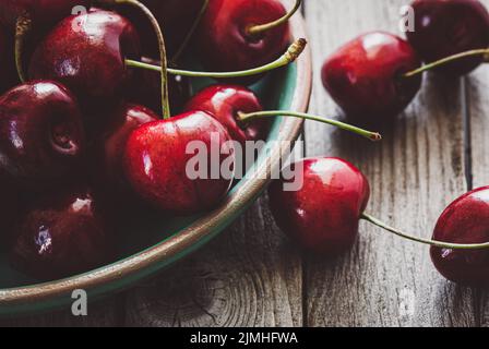 Closeup of sweet cherries in bowl on wooden table, seasonal fruit background Stock Photo