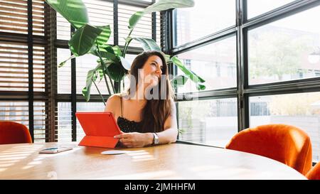 Smiling young woman sitting restaurant with digital tablet Stock Photo