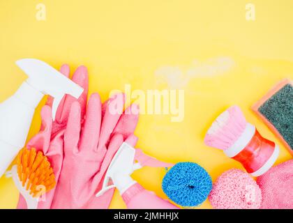 Spray bottle brush sponge pink gloves yellow backdrop Stock Photo