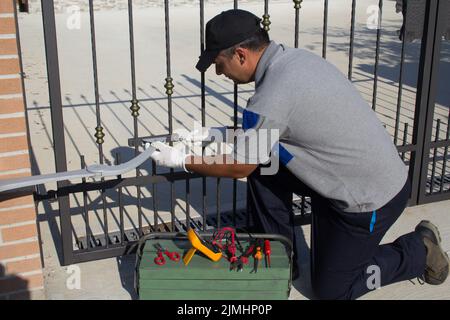 Electrician at work with tools of the trade while assembling and repairing the motor of an automatic gate. Do it yourself homework Stock Photo