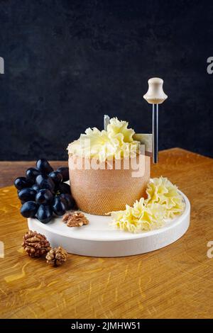 https://l450v.alamy.com/450v/2jmhw51/traditional-tete-de-moine-aged-mountain-cheese-of-the-alps-served-with-grapes-on-a-girolle-on-a-wooden-board-2jmhw51.jpg