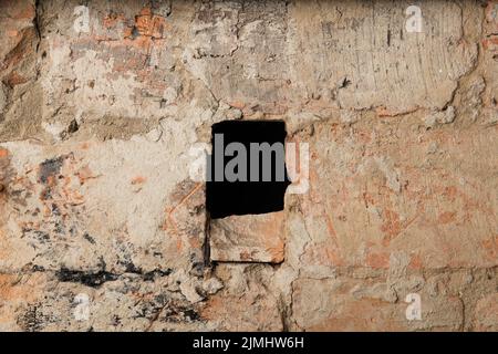 Old red brick wall with a black hole in the middle. The textured background of a vintage brick wall. A panoramic view of an empty wall with copy space can be used for interior design. Stock Photo