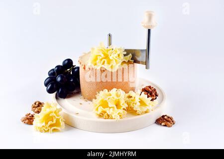 Traditional tete de moine aged mountain cheese of the Alps served with  grapes and walnuts wooden design board with copy space Stock Photo - Alamy