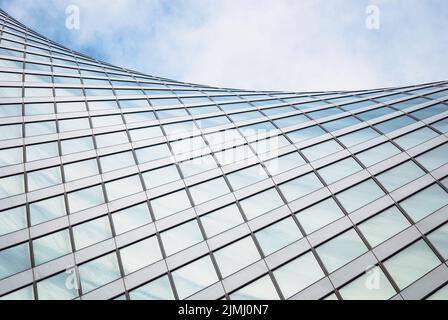 Modern architecture, glass exterior structure, wave shape building detail in blue sky Stock Photo
