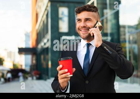 Outdoors business man drinking his coffee talking phone Stock Photo