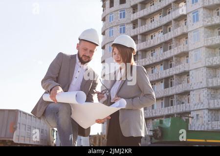 Two architects holding blueprint discussing project while working together Stock Photo