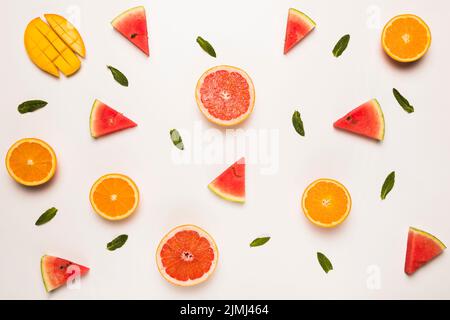 Sliced grapefruit watermelon orange mango green leaves Stock Photo