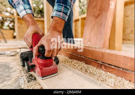 Construction worker sanding down wood piece Stock Photo