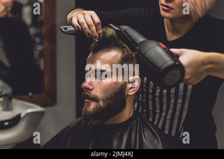 Barber woman drying hair client Stock Photo