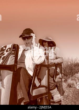 South Africa - August 21 2007: Two-women on back on open-topped safari vehicle in monochrome effect. Stock Photo