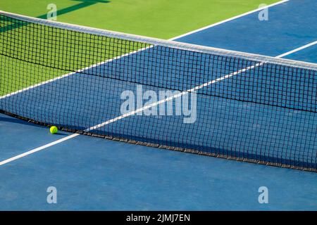 Artificial tennis court. View of the ball lying at the net. Very bright colors of sport arena Stock Photo