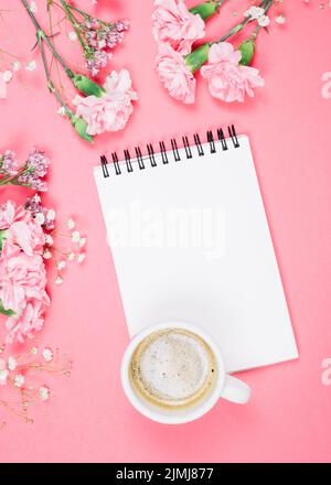 Overhead view coffee cup blank notepad with carnations gypsophila limonium flowers pink background Stock Photo