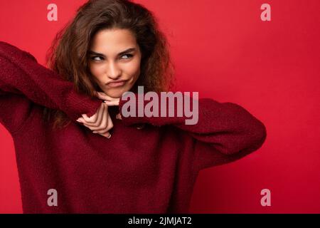 Photo of young funny self-confident beautiful brunette curly woman with sincere emotions wearing casual red pullover isolated on Stock Photo