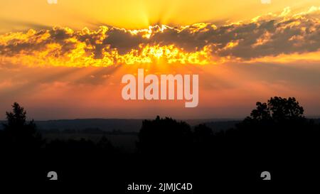 Crimson sunrise (sunset) bright rays of the sun breaking through the clouds Stock Photo