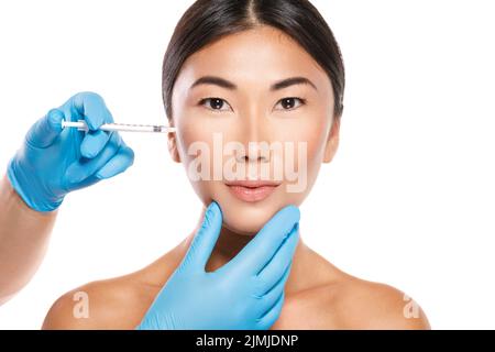 Asian woman during cheekbone modulation or filler injection procedure Stock Photo