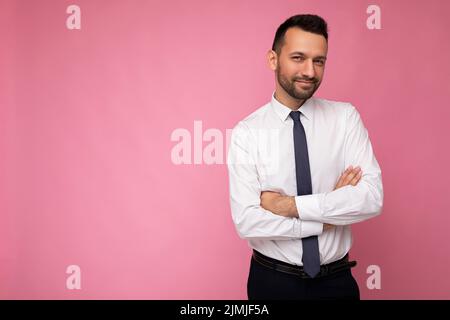 Photo of handsome confident positive brunet man in casual white shirt isolated on pink background with copy space for text Stock Photo