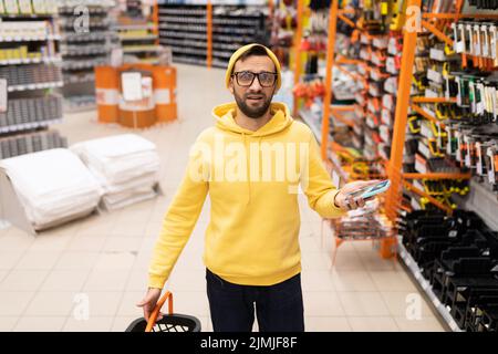 A male customer is lost in a hardware store among a wide range of goods Stock Photo