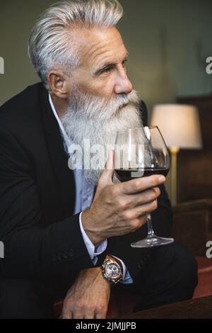 Handsome bearded senior man drinking red wine Stock Photo