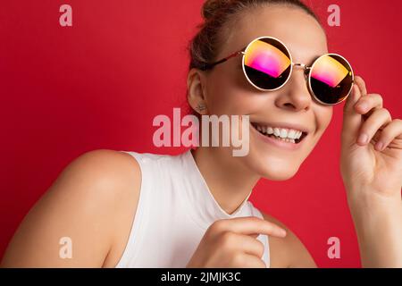 Close-up photo shot of beautiful attractive cute positive happy smiling young blonde woman isolated over red background wall wea Stock Photo