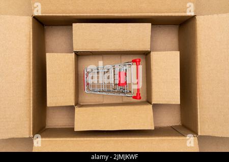 Shopping cart inside open rectangular cardboard box Stock Photo