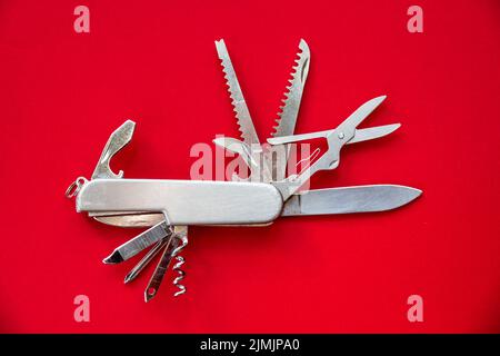 Metallic swiss knife isolated on red Stock Photo