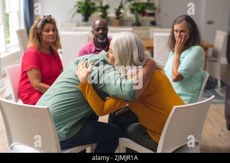 Caucasian senior man and woman embracing during group therapy session Stock Photo