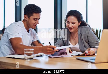 Taking a look at the breakdown of their best creative ideas. two businesspeople going through paperwork together in an office. Stock Photo