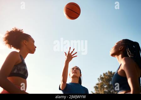 First one to get the ball starts. a diverse group of sportswomen playing a competitive game of basketball together during the day. Stock Photo