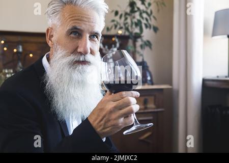 Handsome bearded senior man drinking red wine Stock Photo