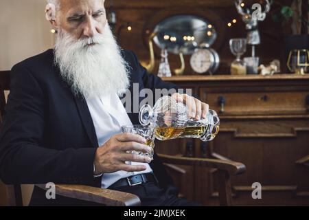 Handsome bearded senior man with a glass of whiskey Stock Photo