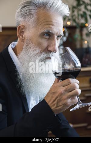 Handsome bearded senior man drinking red wine Stock Photo