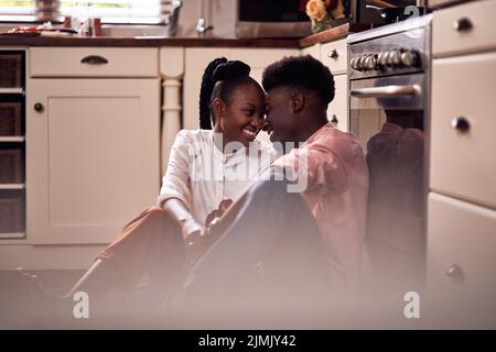 Theyre so in love. Full length shot of an affectionate young couple smiling at each other while sitting in their kitchen at home. Stock Photo
