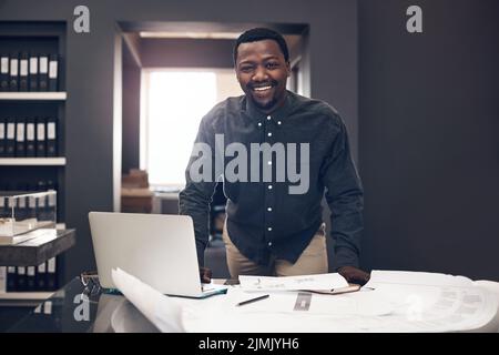 Trust me to get the job done. Cropped portrait of a handsome young male architect smiling while standing behind his desk in a modern office. Stock Photo