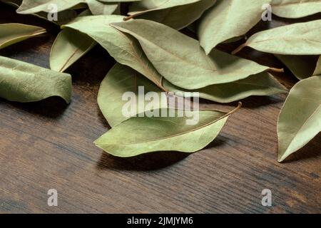 Dry bay leaves scattered on a dark rustic wooden background Stock Photo