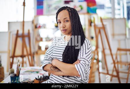 Im an artist, so are you. a beautiful young woman standing with her arms crossed in a art studio. Stock Photo