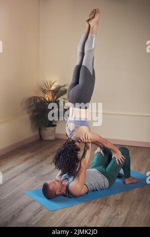 Life is a balancing act. Full length shot of a handsome young man doing acro yoga with his partner in a yoga studio. Stock Photo