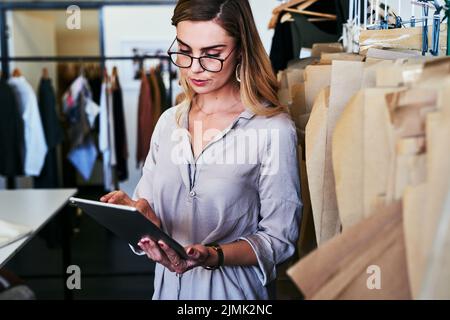 Researching current fashion trends. a young fashion designer using a digital tablet at work. Stock Photo