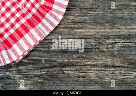 Red checkered towel on the kitchen table. Wooden table background. Stock Photo