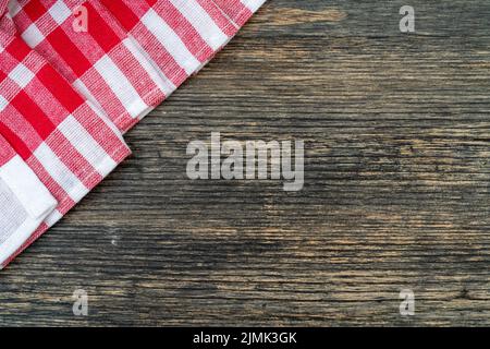Red checkered towel on the kitchen table. Wooden table background. Stock Photo