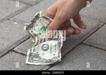 Poor woman picking old and crumpled one dollar bill Stock Photo