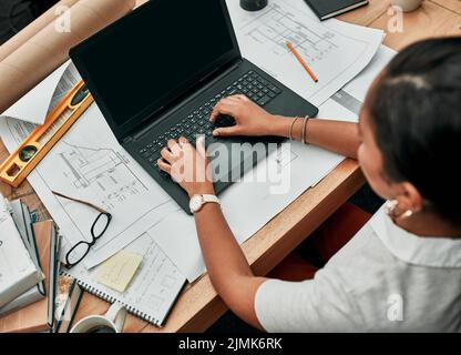 Making progress on all her tasks. High angle shot of an architect working on a laptop in an office. Stock Photo