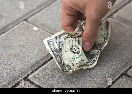 Poor woman picking old and crumpled one dollar bill Stock Photo