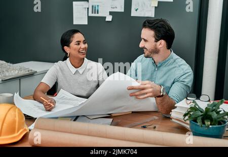 Leave the creative minds to work at it. two architects working with blueprints in an office. Stock Photo