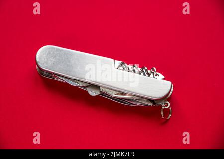 Metallic swiss knife isolated on red Stock Photo