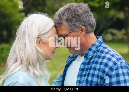 Romantic caucasian senior couple with face to face standing in backyard Stock Photo
