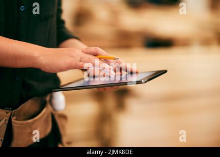 Designing furniture has never been this easy. a an unrecognizable carpenter using a digital tablet in her workshop. Stock Photo